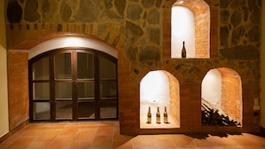 A stone-walled room with a large arched doorway and three small arched windows, each with bottles. - Sabor&arte (Antigua Guatemala)