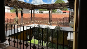 A balcony with a view of terracotta-roofed buildings and a clear sky. - Sabor&arte (Antigua Guatemala)