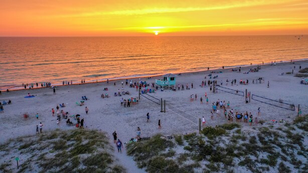 Ein Strand bei Sonnenuntergang mit Menschen und einem Rettungsturm.
