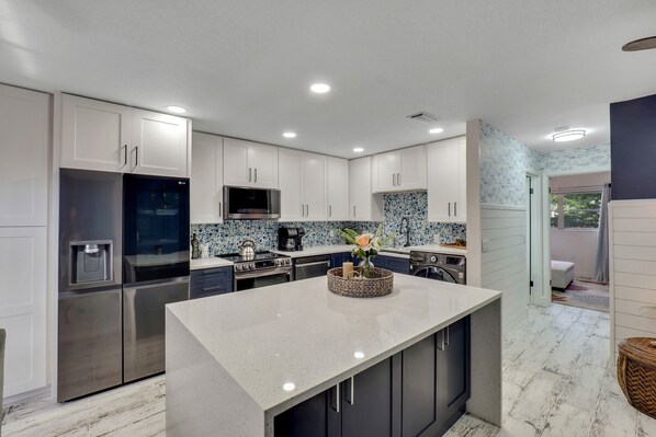 A modern kitchen with white cabinets, stainless steel appliances, and a central island.