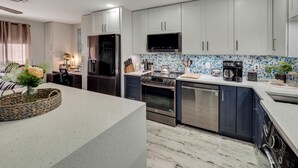 Eine moderne Küche mit weißen Schränken, einem eingebauten Backofen, einer Mikrowelle und einer Kaffeemaschine.
