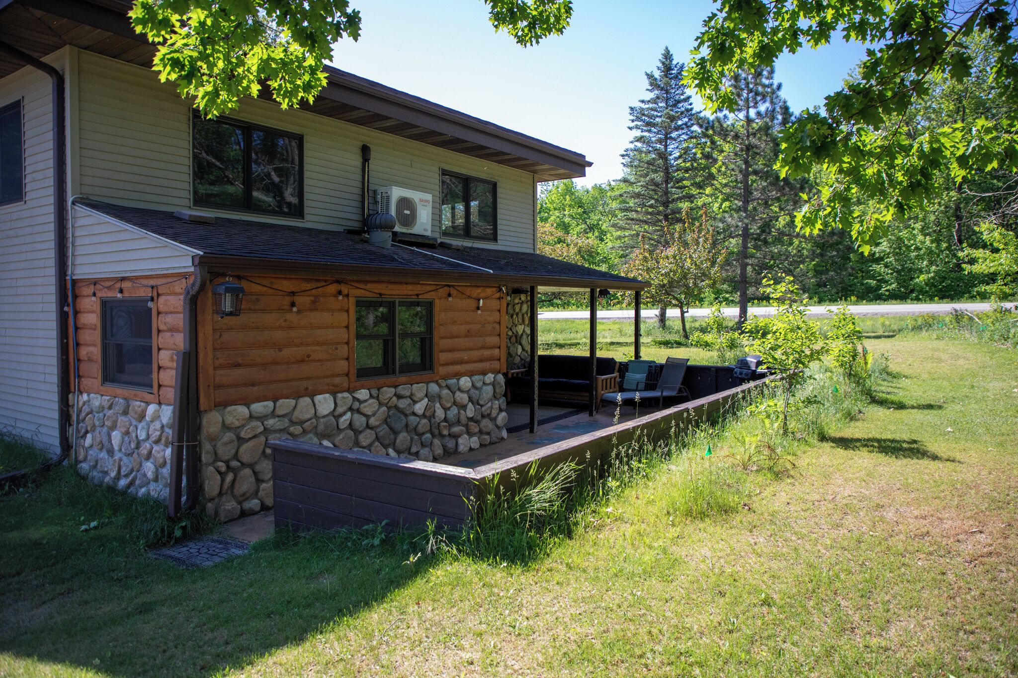Une cabane en rondins avec des fondations en pierre, une véranda et un espace salon extérieur.