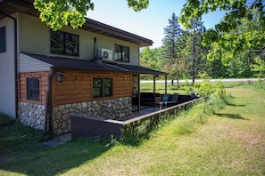 A log cabin with a stone foundation, a covered porch, and outdoor seating.