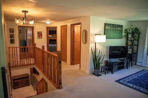 A living room with a staircase, a television, a plant, and a framed picture on the wall.