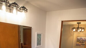 Une salle de bain avec un meuble-lavabo en bois, un évier noir et un miroir doté de luminaires.
