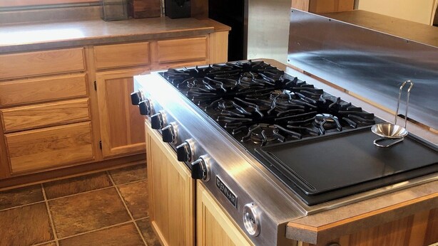 Une cuisine dotée de meubles en bois, d’une cuisinière à gaz de la marque Jenn-Air et d’un réfrigérateur en acier inoxydable.