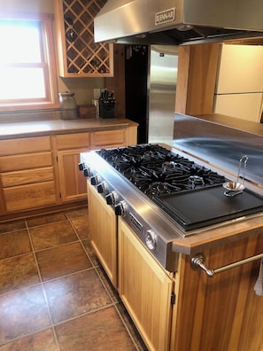 A kitchen with wooden cabinets, a Jenn-Air gas stove, and a stainless steel refrigerator.
