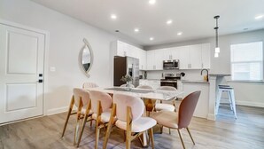 Une cuisine moderne avec des meubles blancs, un îlot central et des appareils électroménagers en acier inoxydable.