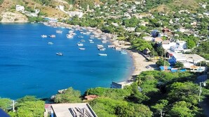 Una cittadina costiera con barche ormeggiate lungo la riva, circondata da colline verdi.