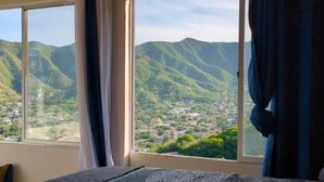 Una stanza con un'ampia finestra che offre vista su un paesaggio montuoso e una città sottostante.