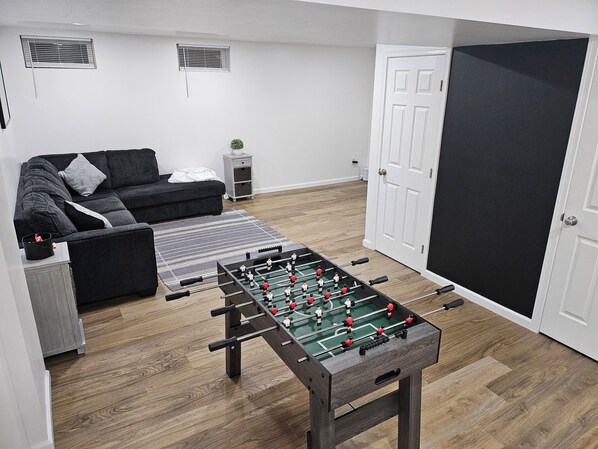 A room with a foosball table, a sofa, and a door. - Near University of Delaware, Christiana Care Hospital, & the Christiana Mall! (Newark)