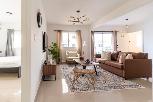 A modern living room with a sofa, a coffee table, a chair, and a small table with a lamp.
