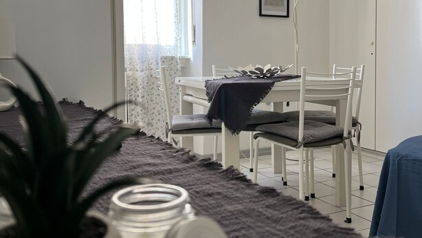 Une pièce comprenant un lit, une table de chevet avec une lampe, une fenêtre avec des rideaux et une chaise.