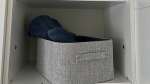 Une armoire blanche avec trois étagères et une boîte de rangement grise.