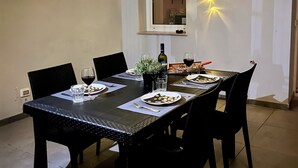 A dining area with a table set for four, featuring black chairs, a white tablecloth, and string lights. - All new, 100 sqm terrace & 5 min walk to the old town & shopping street (Bari)