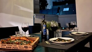 An outdoor dining area with a pizza box, wine glasses, and a bottle of wine on a table. - All new, 100 sqm terrace & 5 min walk to the old town & shopping street (Bari)