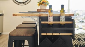 Une cuisine moderne avec un plan de travail en bois, deux tabourets et un luminaire suspendu.