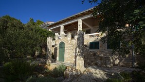 Un edificio de piedra con puerta verde, un porche cubierto y un camino de piedra.