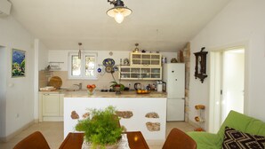 Una cocina con una isla central, una mesa de comedor con sillas y un sofá verde.