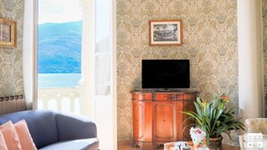 En stue med sofa, fjernsyn, skab og havudsigt.