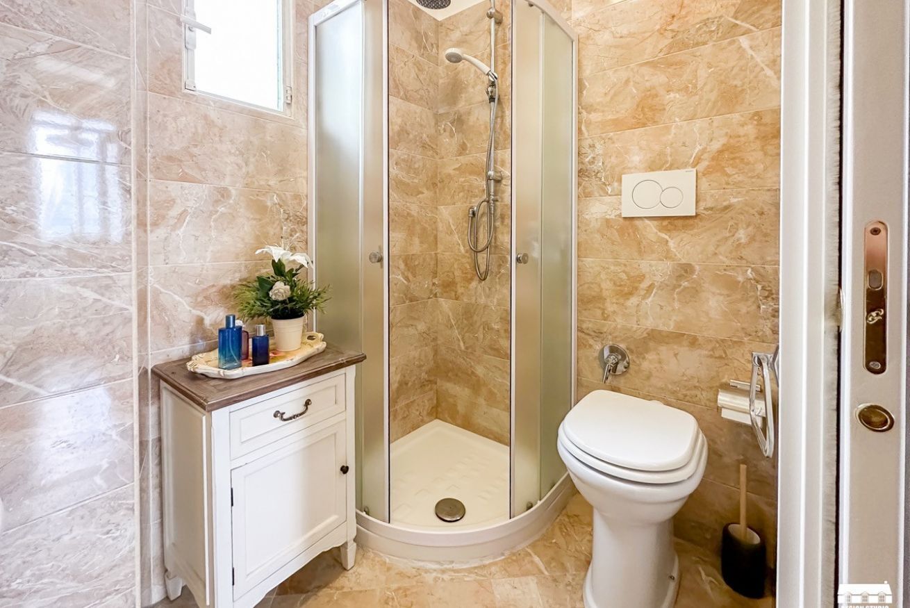 A modern bathroom with a glass-enclosed shower, a white toilet, and a vanity with a mirror and drawers.