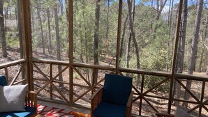 Zona salotto esterna riparata, con ringhiere in legno e vista su una foresta.