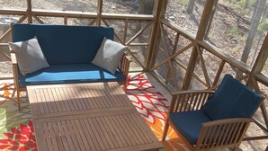 Un'area salotto esterna coperta con tavolo in legno e sedie imbottite blu, circondata da un tappeto decorato.