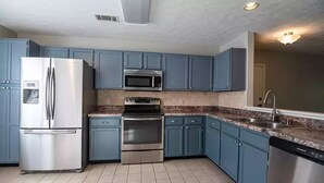 Una cucina con mobili blu, un frigorifero in acciaio inossidabile, un forno a microonde, un forno e una lavastoviglie.