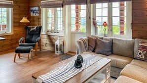 A cozy room with a wooden floor, a sofa, a chair, and a table with candles. - 4 bedroom awesome home in Nordfjordeid (Nordfjordeid)