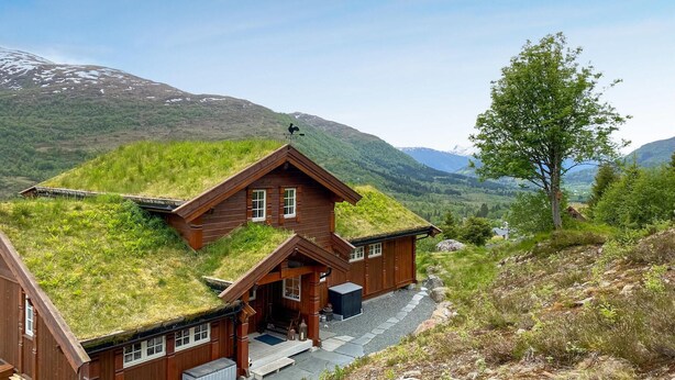 A wooden house with a grass roof, set against a mountainous backdrop. - 4 bedroom awesome home in Nordfjordeid (Nordfjordeid)