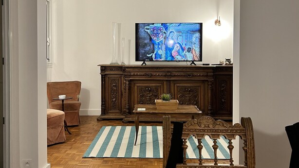 Un soggiorno con televisore, un mobile in legno, un divano e un tavolo da pranzo.
