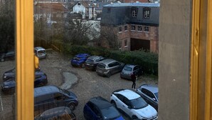 Vista di un parcheggio con diverse auto, un edificio con una torre e un cielo nuvoloso.