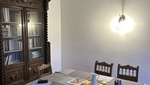 Zona pranzo con tavolo apparecchiato per due, un mobile contenitore in legno con vetrate e un lampadario a parete.