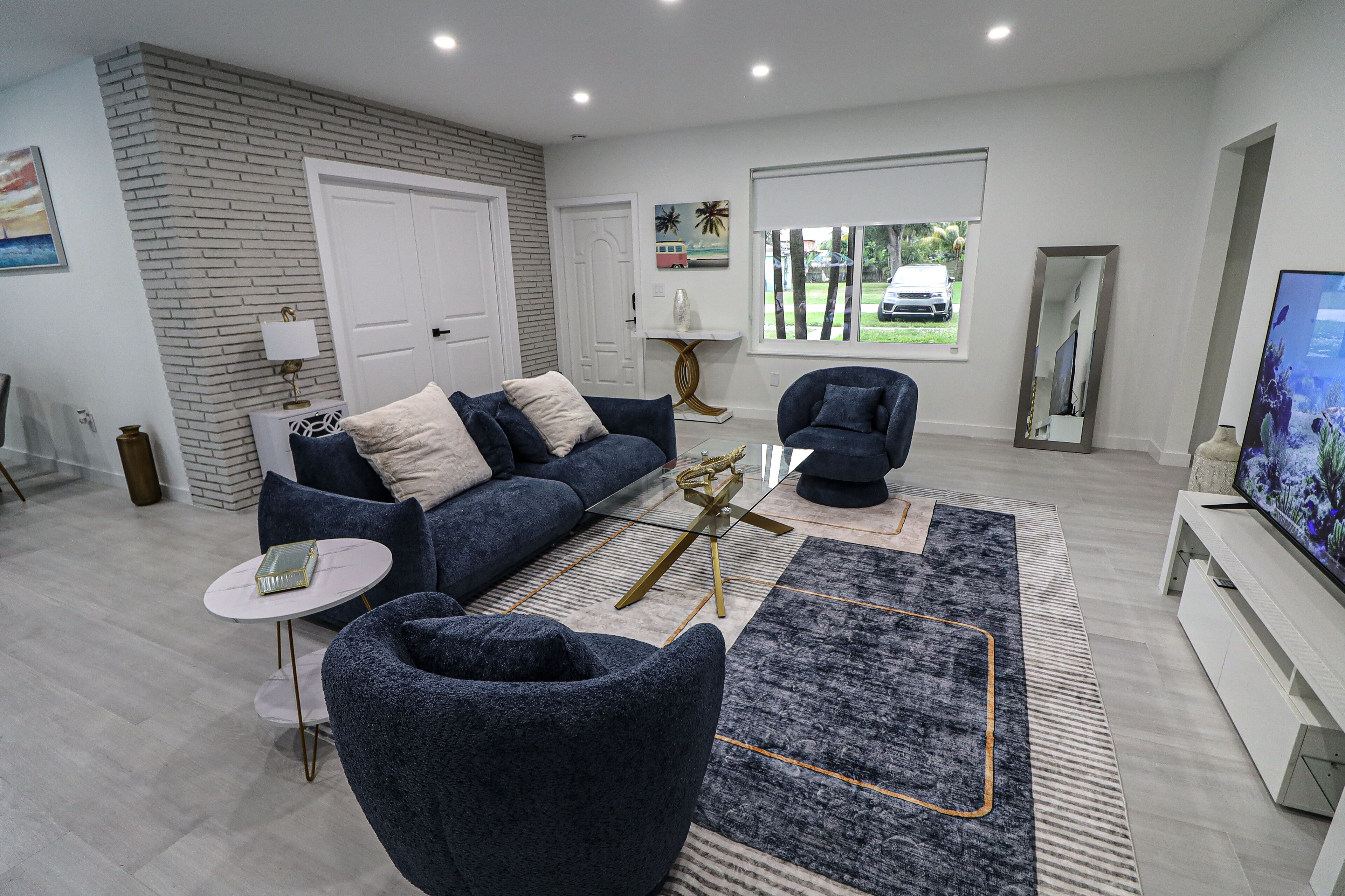 Ein modernes Wohnzimmer mit Sofa, Sessel, Couchtisch und Fernseher.