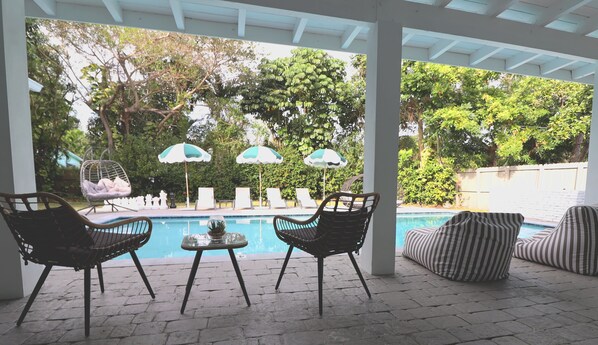 A covered outdoor area with a pool, lounge chairs, and umbrellas. - Villa Cristina in Miami (Miami)