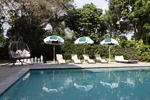 A swimming pool with lounge chairs and umbrellas, surrounded by trees. - Villa Cristina in Miami (Miami)