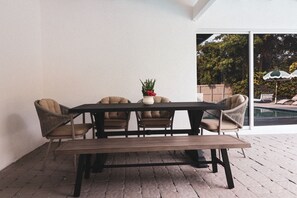 A patio with a wooden table and four chairs, a potted plant, and a view of a swimming pool. - Villa Cristina in Miami (Miami)