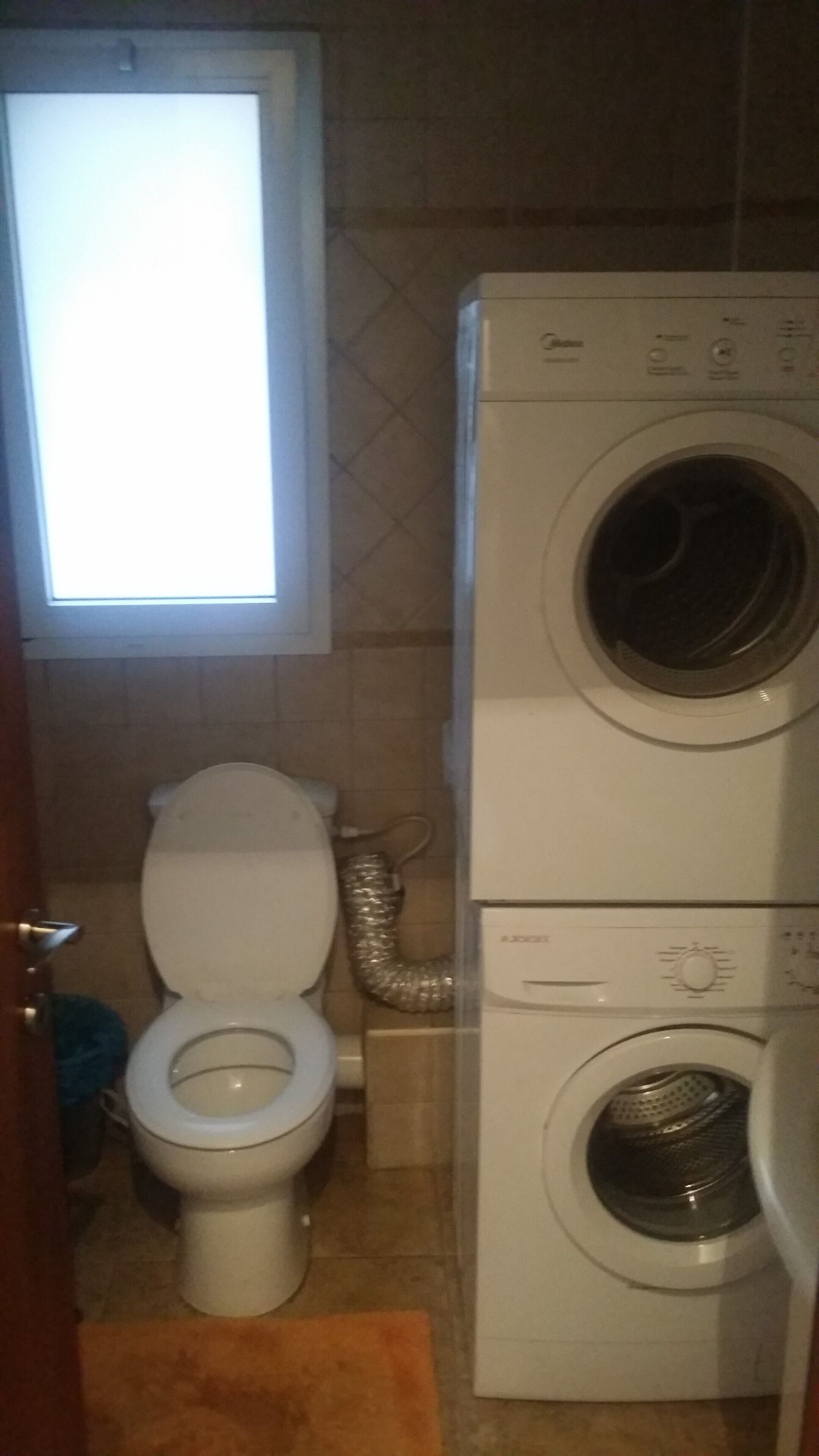Un baño pequeño con inodoro, lavadora y ventana.