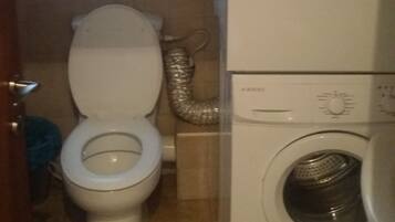 Un baño pequeño con inodoro, lavadora y ventana.