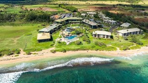 An aerial view of a resort with multiple buildings, a swimming pool, and a beachfront.