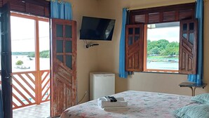 A bedroom with a bed, a TV mounted on the wall, and a view of a river with boats.