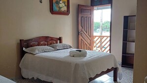 A bedroom with a bed, a nightstand, a wooden door, and a window.