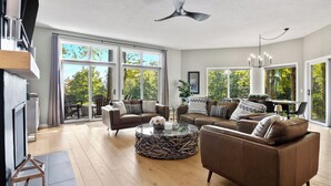 Een ruime woonkamer met een grote glazen deur die leidt naar een balkon, een plafondventilator en een moderne kroonluchter.