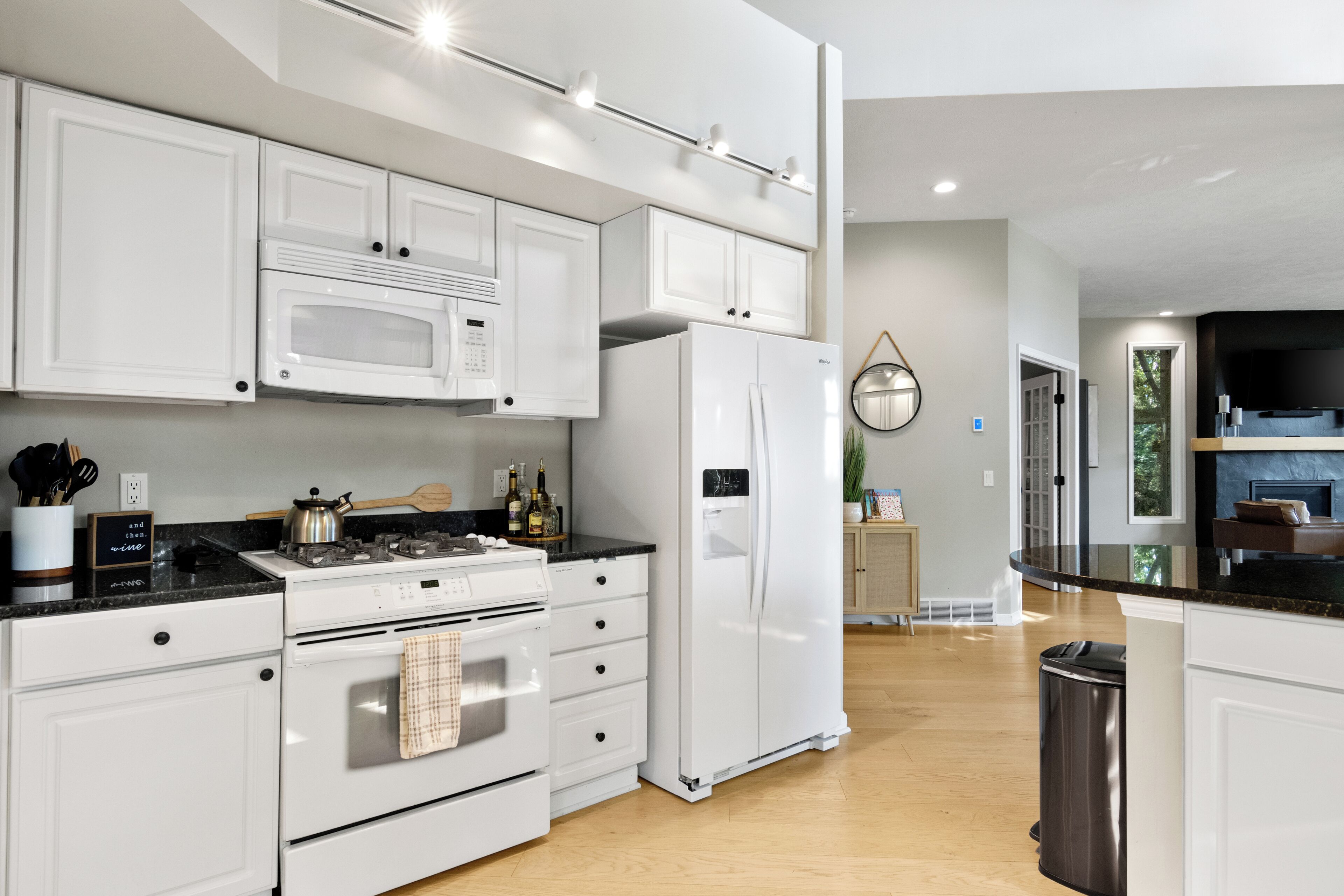 A modern kitchen with white cabinetry, a microwave, stove, oven, and refrigerator.