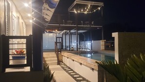 An outdoor swimming pool area with a covered seating area and steps leading to a door. - Cozy and Peacefull  (Aguadilla)