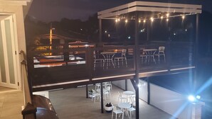 A multi-level outdoor terrace with tables and chairs, string lights, and a view of the surrounding area. - Cozy and Peacefull  (Aguadilla)