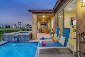 Un área de piscina con jacuzzi, sillas de descanso y una parrilla.