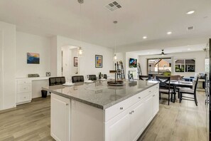 Una cocina amplia con una isla grande, armarios blancos y un comedor con vistas.