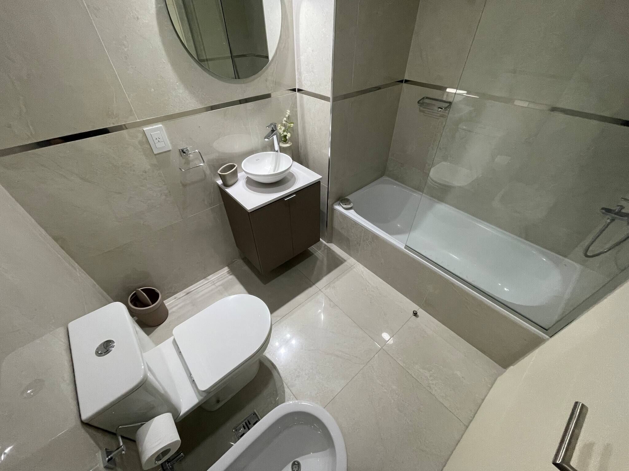 Une salle de bain moderne équipée de toilettes, d’un bidet, d’un lavabo et d’une douche à parois de verre.