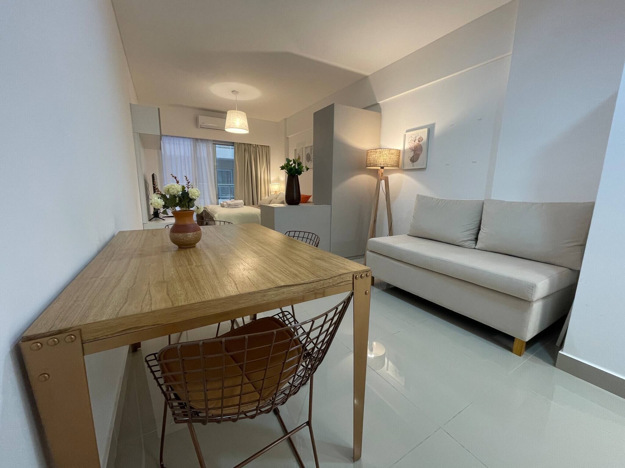 A modern living room with a wooden dining table, a sofa, and a floor lamp.